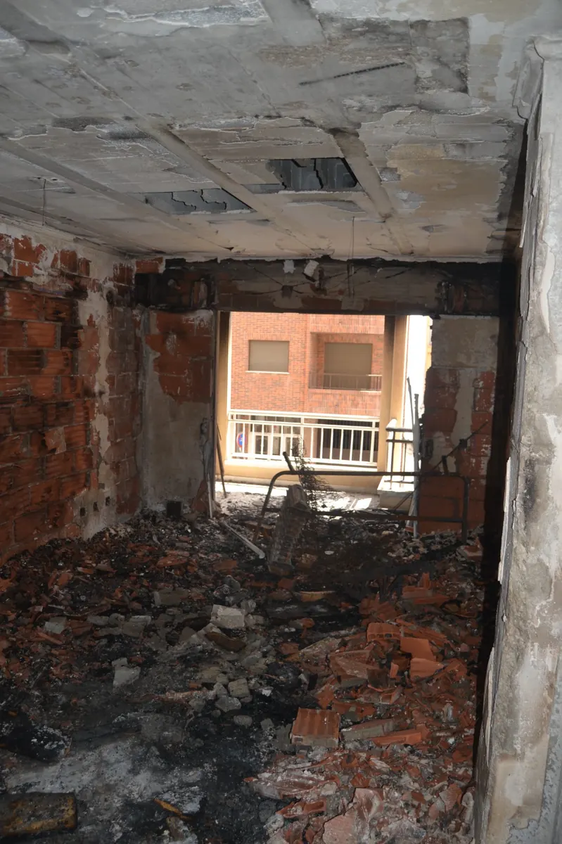Caso real en Getafe: salón con paredes de ladrillo expuestas y residuos de combustión, antes de la intervención de limpieza después de incendio